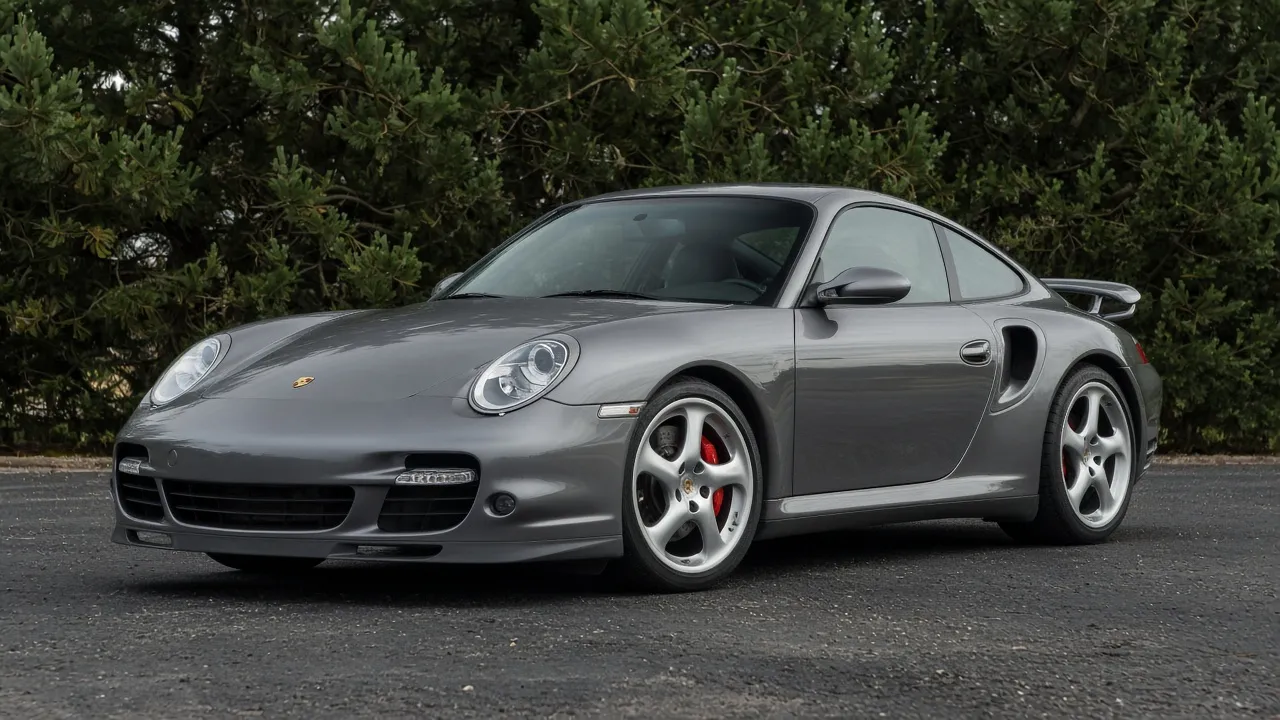 Front three-quarter of a Seal Grey Porsche 996 Turbo with Aerokit wing and Turbo Twist wheels.